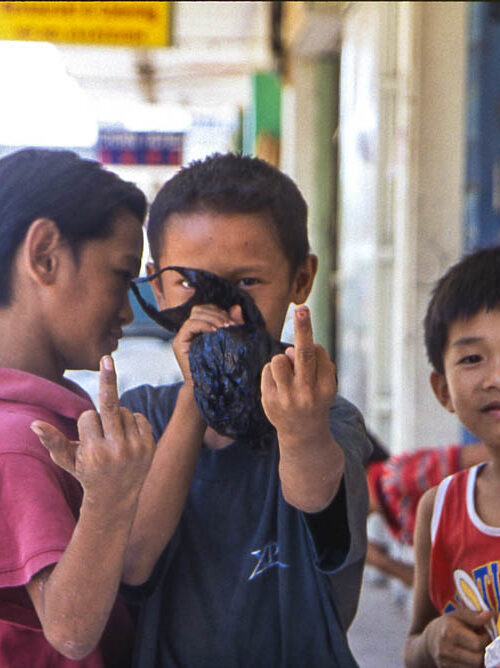 Three kids showing middle fingers in the streets