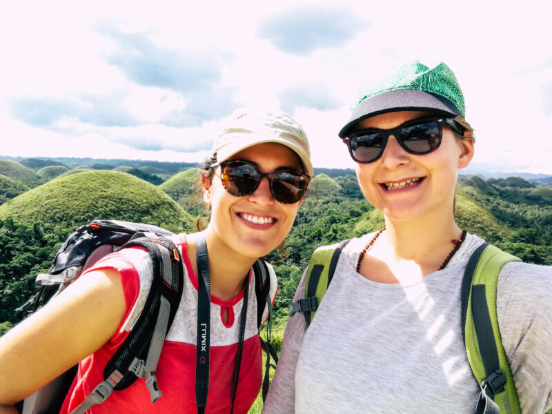Isito and friend Bine smiling in front of the chocolate hills
