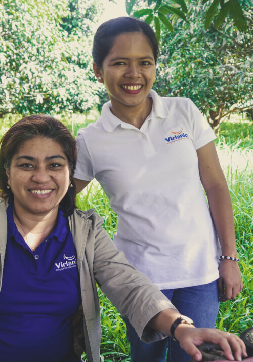 Project manager Adelle Lemay and Admin Officer Rezza May Bolo smiling with a mango plantation in the background