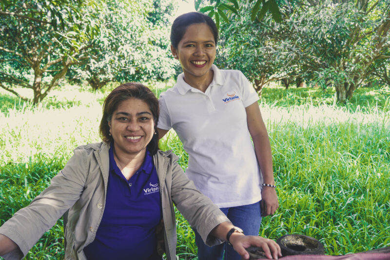 Project manager Adelle Lemay and Admin Officer Rezza May Bolo smiling with a mango plantation in the background