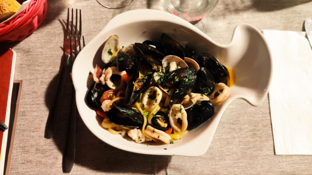 Pasta vongole with squid rings and persil on a plate in fish form