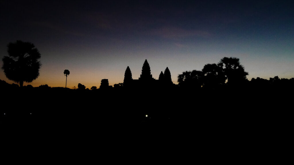 The temple complex of Angkor Wot in black during a colorful sunrise