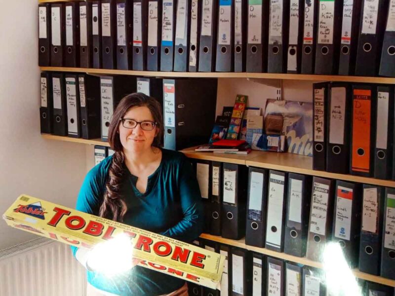 Birgit Brugger holding a 1-meter long Toblerone package in front of her chocolate wrapper collection